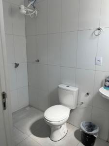 a white bathroom with a toilet and a sink at Kitnet aconchegante próximo a unesp in Botucatu