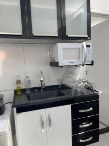 a kitchen with a sink and a microwave at Kitnet aconchegante próximo a unesp in Botucatu