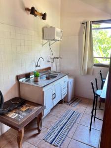 a small kitchen with a sink and a table at Micas House in Ilhabela