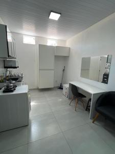 a white kitchen with a table and a desk at Kitnet aconchegante próximo a unesp in Botucatu +5 photos