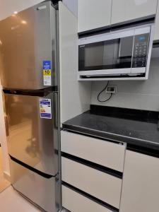 a stainless steel refrigerator in a kitchen with a microwave at دقيقه للبحيره أقامه فندقيه مدينتي بريفادو madinaty privado in Madinaty