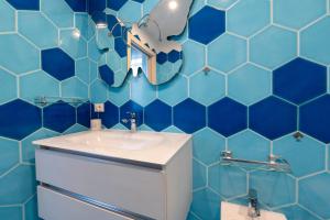 a blue tiled bathroom with a sink and a mirror at Smeraldo in Palau