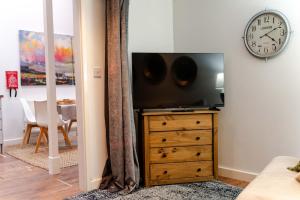 a living room with a tv on a dresser and a clock at Stylish Loft in Stockport - Free Parking - 10 min to Manchester - Flat 1 in Stockport
