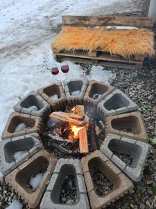 a fire pit with two glasses of wine and snow at Cazare la fermă in Galeşu