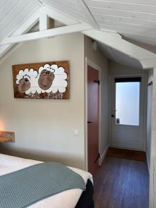 a bedroom with a painting of a sheep on the wall at Beach House Texel in De Koog