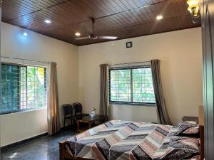 a bedroom with a bed and two windows at Lake View in Kundapur