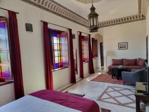 a bedroom with a bed and a couch and windows at Riad Batchisarai in Fez