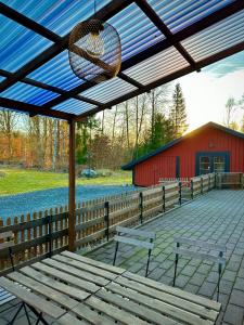 a pavilion with benches and a chandelier and a red barn at Barts house in Länshult +10 photos