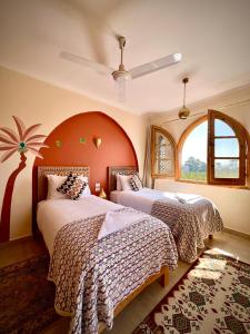 a bedroom with two beds and a large window at Dar Lina Guesthouse Luxor in Luxor