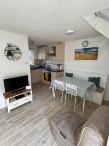 a living room with a table and a kitchen at 20 Strawberry Hill cosy cottage sleeps 5 in Hayle