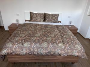 a bed with a brown comforter and two night stands at Nuvola Hosting in Segrate