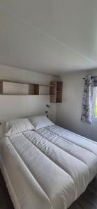 a large white bed in a white bedroom at Monpetitmobilhome in Ascarat +3 photos