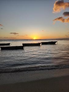 three boats in the water at sunset on the beach at Villa Orchidees-Albion in Albion