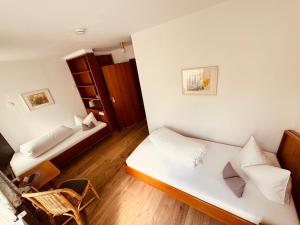 a small room with two beds and a chair at Kaiserstühler-Hof in Breisach am Rhein