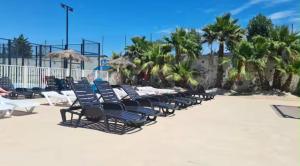 a row of lounge chairs on a beach with palm trees at Au Valras plage in Sérignan