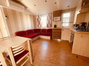 a living room with a red couch and a kitchen at Au Valras plage in Sérignan