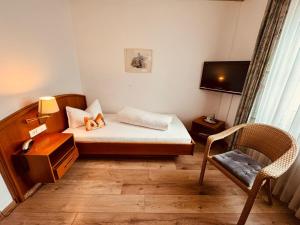 a small room with a bed and a chair at Kaiserstühler-Hof in Breisach am Rhein