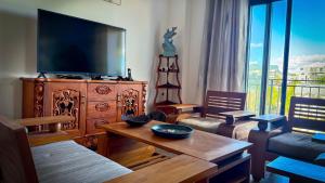 a living room with a large television and a table at Le Verger Sur Mer in Flic-en-Flac