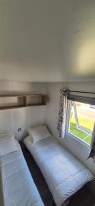 two beds in a room with a window at Monpetitmobilhome in Ascarat