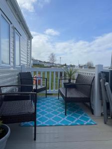 a balcony with two chairs and a blue rug at JSNHolidays at Craig Tara Holiday Park in Ayr