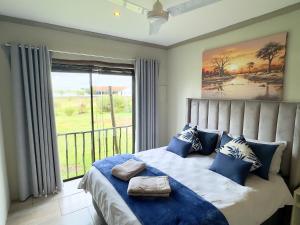 a bedroom with a bed with blue pillows and a window at Vaal Dam Getaway in Denysville