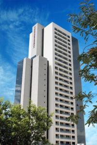 a tall white building with trees in front of it at Flat Valedo no Vivence Suites em Palmas in Palmas