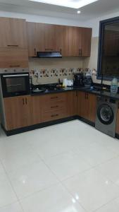 a kitchen with wooden cabinets and a washer and dryer at تجزئة الفتح 925 خريبكة 4 in Khouribga