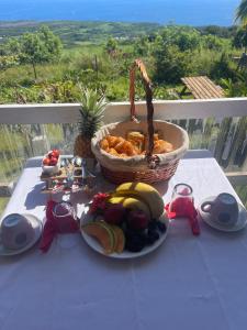 a table with a basket of food and a plate of fruit at Ô Balcon in Sainte-Rose