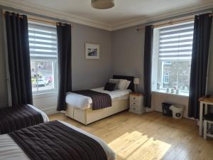 a bedroom with two beds and two windows at The Havelock in Nairn