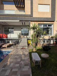 a building with a pool and a patio with benches at Exceptional Villa Pool in Oujda