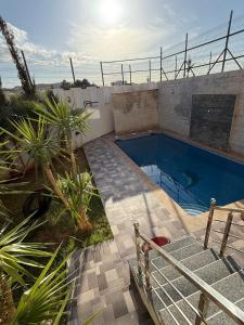 a swimming pool in a yard with palm trees at Exceptional Villa Pool in Oujda