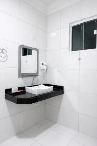 a white bathroom with a sink and a mirror at CS2 - Ampla - Suítes e Ar-Cond em Todos os Quartos in Juazeiro do Norte +23 photos