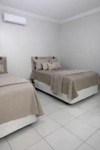 two beds in a room with white walls at CS2 - Ampla - Suítes e Ar-Cond em Todos os Quartos in Juazeiro do Norte