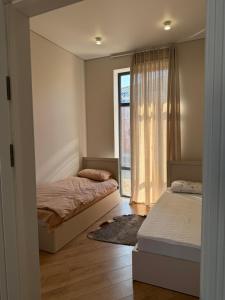 a bedroom with two beds and a window at Коттедж Alfa in Koshkolʼ