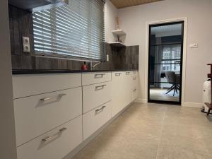 a kitchen with white cabinets and a large window at Villa France in Sevenum