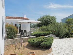 a patio with an umbrella and chairs and bushes at Renovated villa by the ocean in Barbâtre