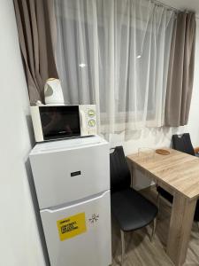 a microwave sitting on top of a refrigerator next to a table at Beregi Apartman in Tiszaújváros +34 photos