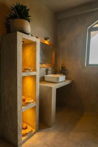 a bathroom with a sink and a shelf with a mirror at BUKU BUKU by Bara Beach in Galle