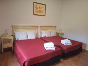 two beds in a room with red sheets at Cantinho do Lello in Bragança