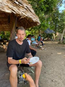 a man sitting on a bench holding a plate at BriBri AdvenTOURS in Tapantí