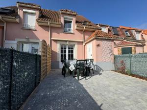 a patio with tables and chairs in front of a house at L'Eclipse in Fort-Mahon-Plage