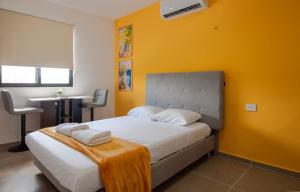 a bedroom with a bed with a yellow wall at X Mahaná Apartamentos Temáticos in Mérida