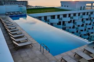 a swimming pool on the roof of a building with chairs at Sea Reflections in Infinity Pool & Spa Resort in Mamaia Sat/Năvodari