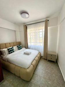 a bedroom with a large bed with a large window at brigit's home in Kisumu