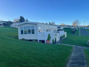 a white house on a green field with a yard at JSNHolidays at Craig Tara Holiday Park in Ayr