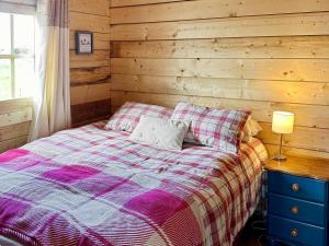 a bedroom with a bed with a wooden wall at Wind Hall Log Cabin in Gosforth