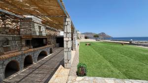 a building with a grass field next to the ocean at Magic estate on the wave 2 by Villa Lagkadaki in Kotronas