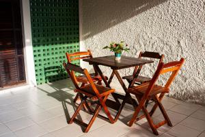 a wooden table with four chairs and a vase with flowers at Pousada Aconchego Manaíra in João Pessoa