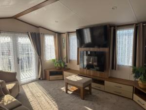 a living room with a flat screen tv and a couch at Golden Anchor 6 Berth Caravan, Chapel St Leonards, 22 Wild Flower Meadow in Chapel Saint Leonards