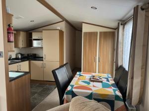 a kitchen with a table and chairs and a kitchen with a kitchen at Golden Anchor 6 Berth Caravan, Chapel St Leonards, 22 Wild Flower Meadow in Chapel Saint Leonards